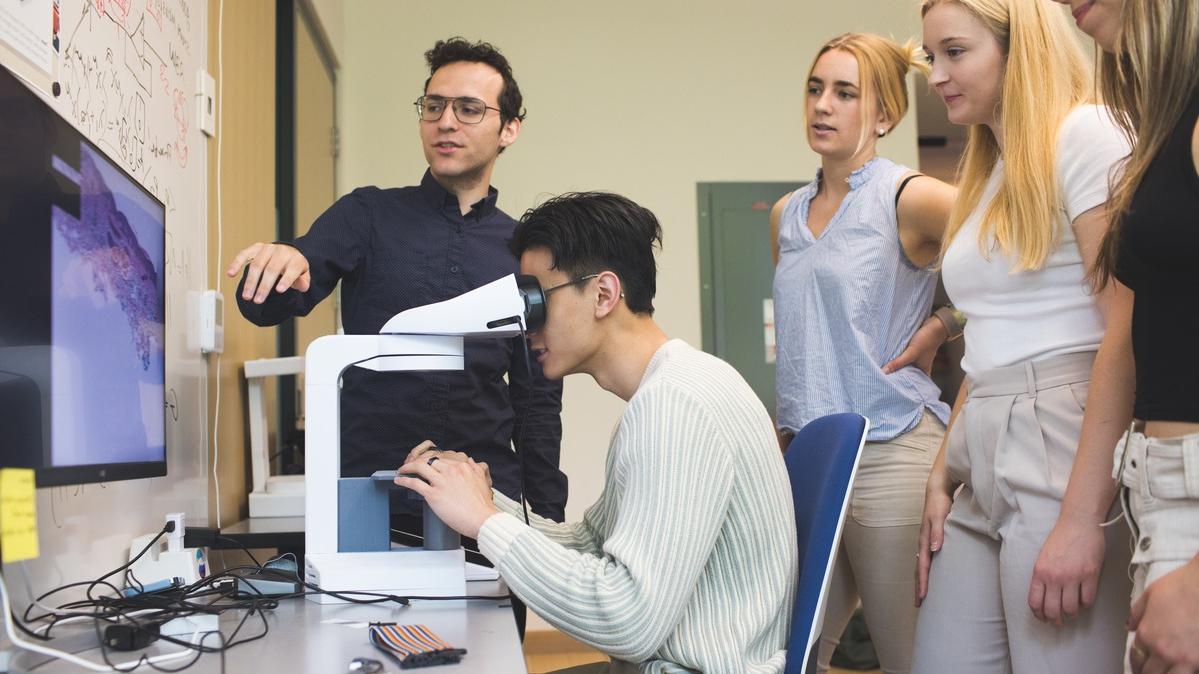 A student uses the SmartScope microscope under Carney's direction as others watch.